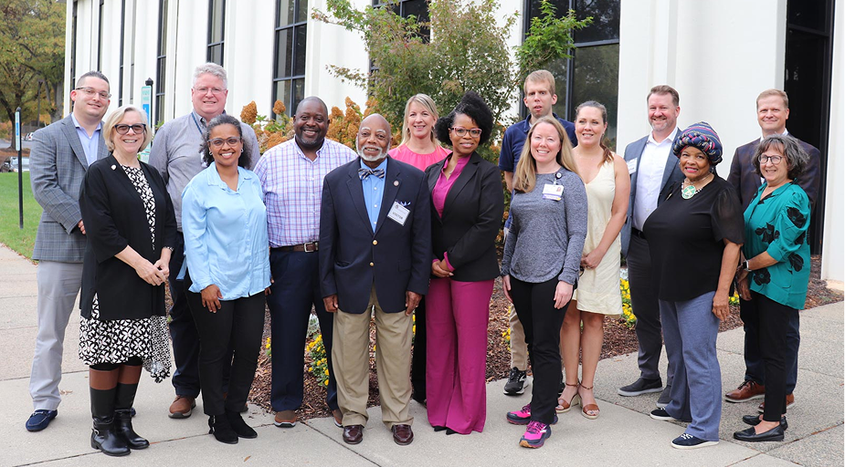 A diverse group of people, the state rehabilitation council members, stand in front of a building