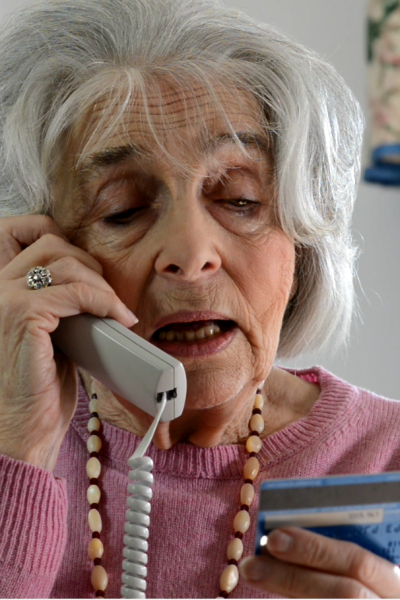 An elderly woman reading her credit card number on a phone call
