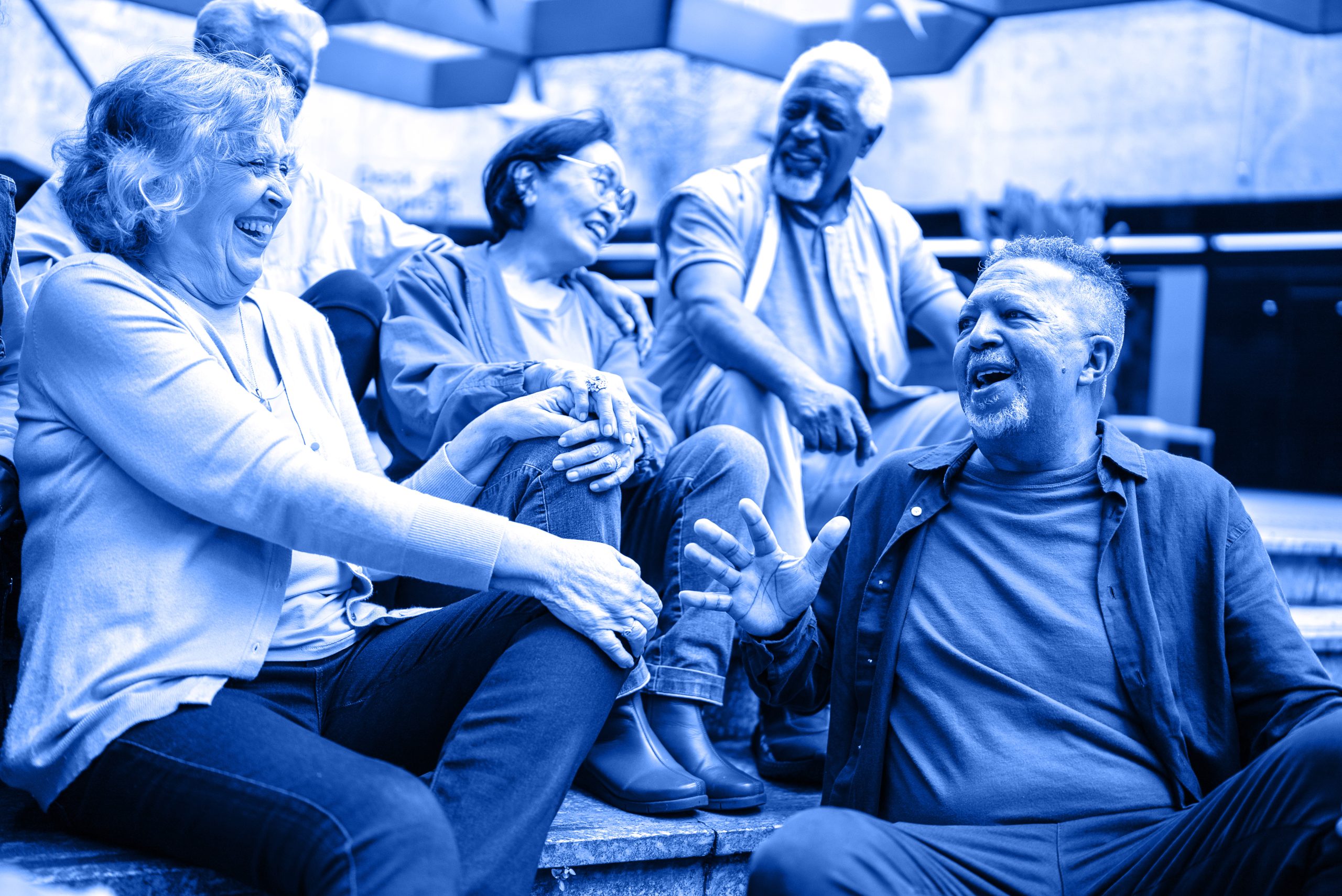 Diverse group of older people talking and laughing with one another as they sit on steps outside